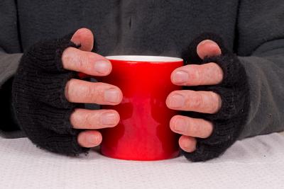 Hands in gloves holding a hot drink